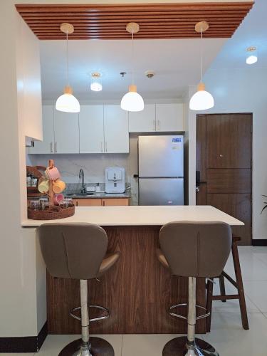 a kitchen with a white counter and two bar stools at Cozy Corner at Manhattan Heights Tower B 2BR ,2BA Amazing View in Manila