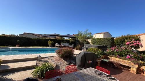 un patio avec une table et des chaises à côté d'une piscine dans l'établissement Chez lolo, à La Regrippière