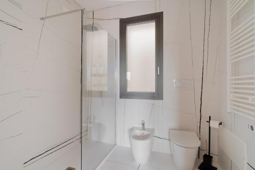 a white bathroom with a toilet and a window at Glass House - Smart Rooms & Parking in Lecce