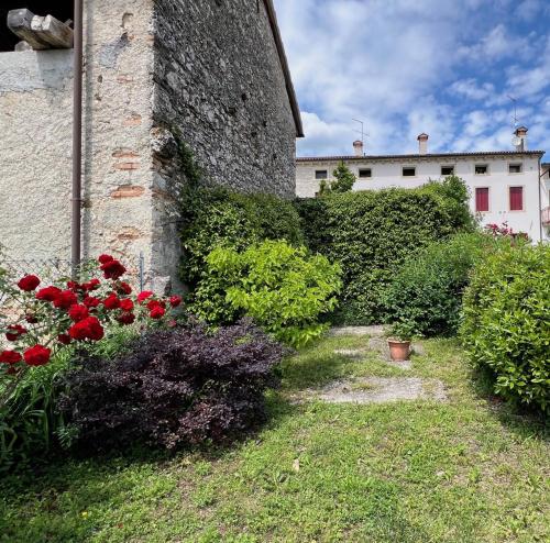 a garden with red flowers and plants next to a building at Casa Agostini Bed and Breakfast in Farra di Soligo