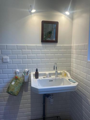 une salle de bain blanche avec un lavabo et un miroir dans l'établissement Appartement pour 2 personnes, gîte La Loba, à Semur-en-Auxois