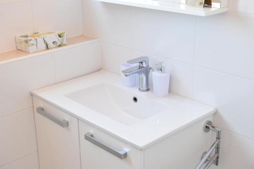 a bathroom with a white sink and white tiles at Villa Luger 1. Stock in Ražanj