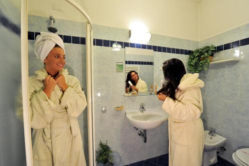 a woman in a bathroom looking at herself in the mirror at Residence Veliero in San Mauro a Mare