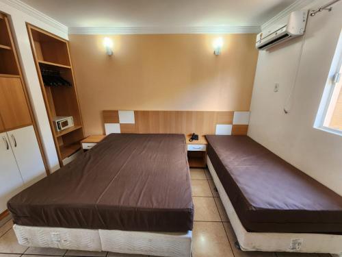a bedroom with two beds and a window at diRoma Fiori - Apartamentos JN in Caldas Novas