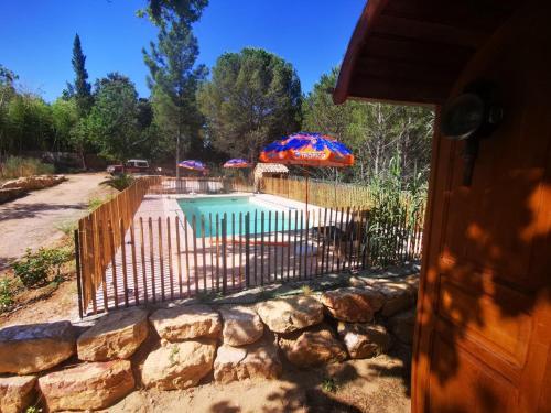 une clôture à côté d'une piscine avec un parasol dans l'établissement Gite provençal de Montigal, à Bagnols-sur-Cèze