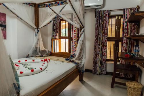a bedroom with a bed in a room with windows at Shoki Shoki Guest House in Zanzibar City