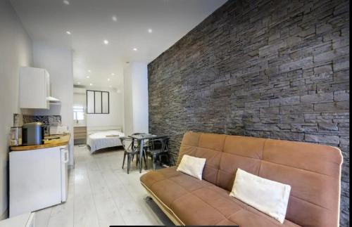 un salon avec un canapé et un mur de briques dans l'établissement studio centre port de nice, à Nice