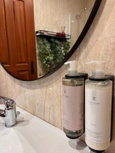 two bottles ofodorizers on a bathroom sink in front of a mirror at CASA das Leiras in Vieira do Minho