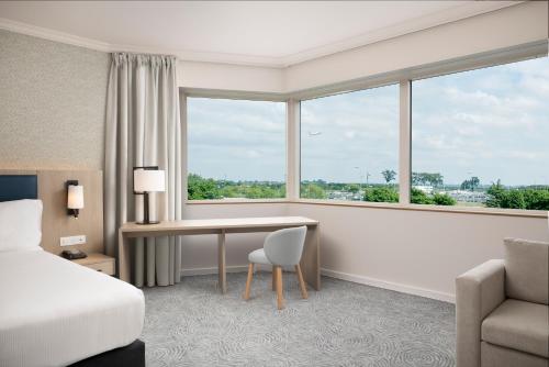 a hotel room with a bed and a desk and a window at Hilton Paris Charles De Gaulle Airport in Roissy-en-France