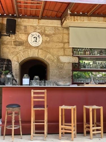 a bar with three wooden stools in front of it at Beit Faris Wa Lucia Guesthouse Byblos in Jbeil