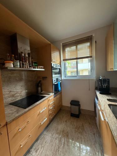 une cuisine avec des armoires en bois, un évier et une fenêtre dans l'établissement Appartement Roland Garros PSG, à Boulogne-Billancourt