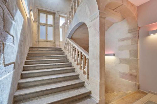 a stone staircase in a building with a window at Appart'hôtel Odalys City - Dijon Centre Les Cordeliers in Dijon