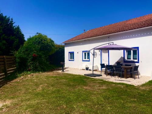 a white house with a table and an umbrella at Pine 3 Inn, holiday home, activities and more in Boavista dos Pinheiros