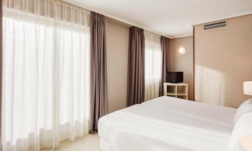 a bedroom with a white bed and a large window at Sercotel Togumar in Madrid