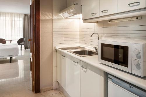 a white kitchen with a sink and a microwave at Sercotel Togumar in Madrid