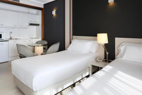 a hotel room with two beds and a kitchen at Sercotel Togumar in Madrid