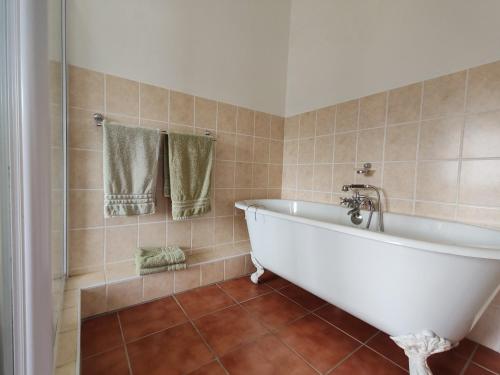 a bathroom with a white bath tub and tiles at The River House - Main House in Colchester