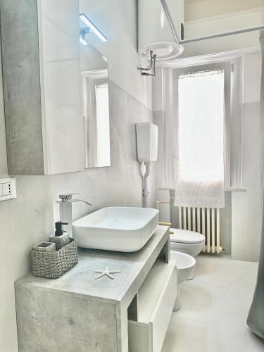 a white bathroom with a sink and a toilet at Appartamento Debbis Home Misano Adriatico in Misano Adriatico