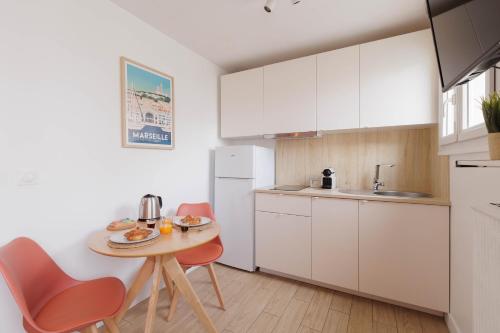 une cuisine avec une table et des chaises et une petite table avec de la nourriture dessus dans l'établissement Une Escapade au Vieux Port, à Marseille