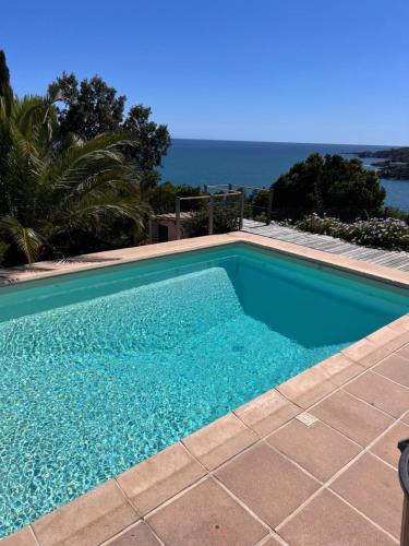 une piscine bleue avec l'océan en arrière-plan dans l'établissement Villa d'exception vue mer avec piscine privée, à Saint-Raphaël