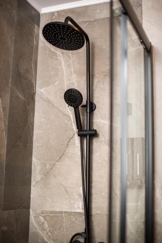 a shower with a black shower head on a wall at YourCastle Premium Apartments in Alexandroupoli