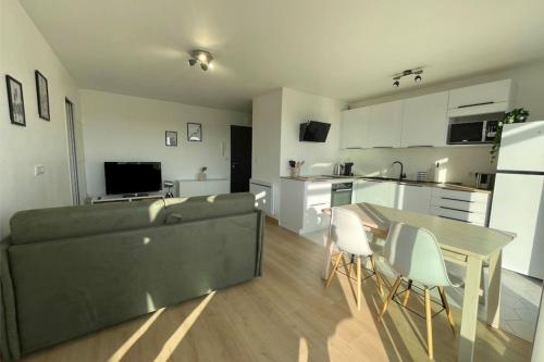 un salon et une cuisine avec un canapé et une table dans l'établissement Charming modern apartment with terrace, à La Rochelle