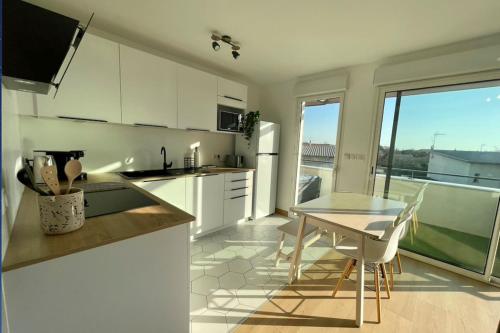 une cuisine avec des placards blancs et une table avec vue dans l'établissement Charming modern apartment with terrace, à La Rochelle
