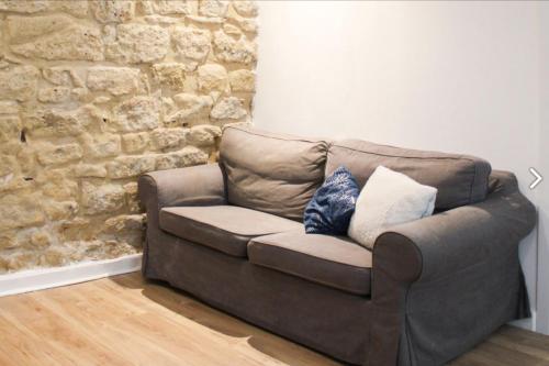 - un canapé brun dans une chambre dotée d'un mur en pierre dans l'établissement Comfortable apartment in the heart of Paris, à Paris
