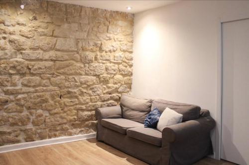 - un salon avec un canapé et un mur en pierre dans l'établissement Comfortable apartment in the heart of Paris, à Paris
