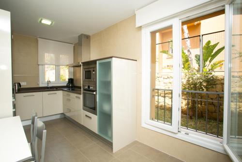 a kitchen with white cabinets and a large window at Villas Altos De Marbella in Marbella