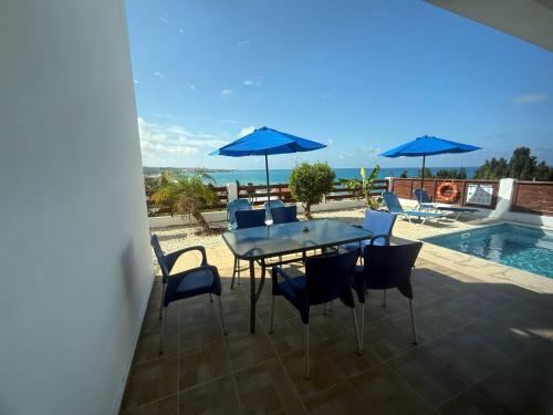 eine Terrasse mit Tisch und Stühlen und einem Pool in der Unterkunft Villa Aqua Sunrise 1km From Beach With Sea Views in Coral Bay