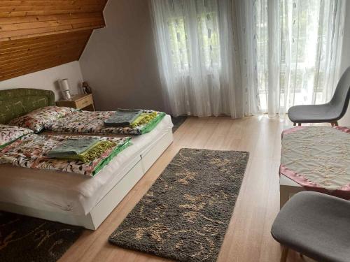 a bedroom with a bed and a chair and a rug at Linda ház in Siófok