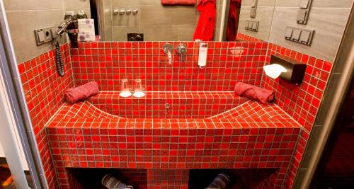 a red tiled bathroom with a red counter top at PLAZA INN stays design Dortmund in Dortmund