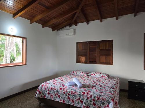 a bedroom with a bed with a red blanket and a window at Finca Hotel Galilea Doradal in Doradal
