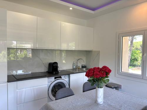 une cuisine avec une machine à laver et un vase de roses rouges dans l'établissement Luma - Logement Climatisé Proche Centre & Plages, à Saint-Tropez