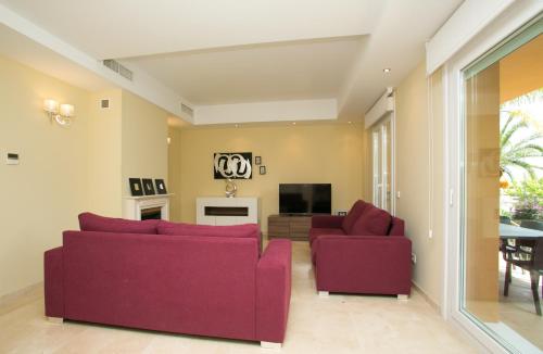a living room with two purple couches and a tv at Villas Altos De Marbella in Marbella
