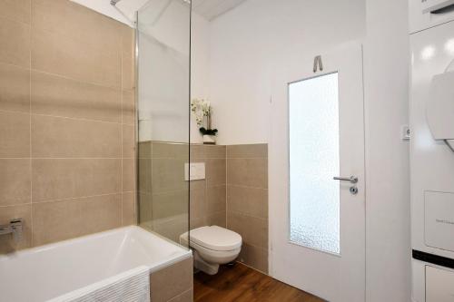 a bathroom with a tub and a toilet and a sink at Apartmenthaus Schlosspark in Worms