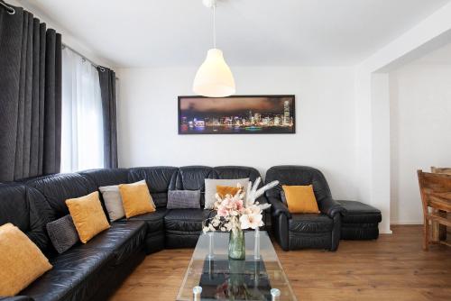a living room with a black leather couch and a glass table at Apartmenthaus Schlosspark in Worms