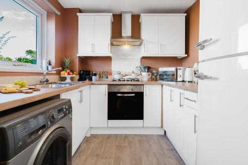 a kitchen with white cabinets and a dishwasher at Quiet & Stylish 2-Bed House with Garden & Free Parking in Cwm-brân