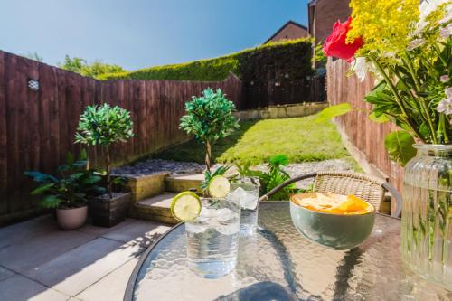 a glass table with a vase of water on a patio at Quiet & Stylish 2-Bed House with Garden & Free Parking in Cwm-brân