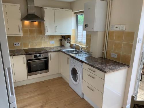 a kitchen with a sink and a washing machine at Beautiful home near to Musgrove Park Hospital in Taunton