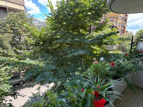 a tree in a garden with flowers and plants at AL Apartments Tirana in Tirana