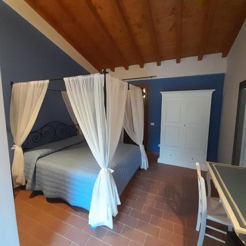 a bedroom with a bed with curtains and a table at Agriturismo La Sarticola in Luni
