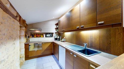 une cuisine avec des armoires en bois et un évier dans l'établissement Les Fables de la Fontaine - centre historique, à Sarlat-la-Canéda