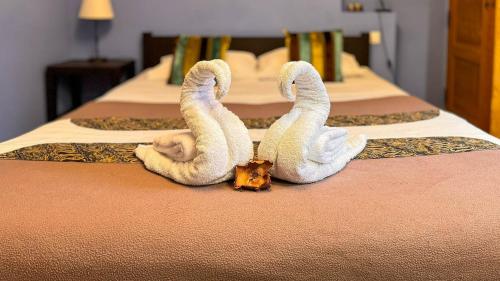 2 cygnes faits de serviettes assises sur un lit dans l'établissement Les Fables de la Fontaine - centre historique, à Sarlat-la-Canéda