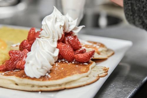 a plate of pancakes with strawberries and whipped cream at Holiday Inn Hotel & Suites Regina by IHG in Regina