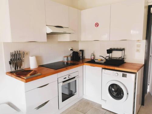 une cuisine avec des armoires blanches et une laveuse et une sécheuse dans l'établissement CAP D'AGDE Maison mitoyenne T2 cabine PISCINE PARKING proche village naturiste, au Cap d'Agde