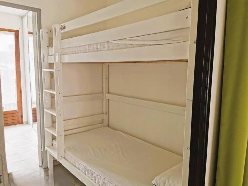 Ce lit superposé blanc se trouve dans un dortoir. dans l'établissement CAP D'AGDE Maison mitoyenne T2 cabine PISCINE PARKING proche village naturiste, au Cap d'Agde