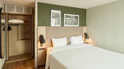 a bedroom with a large white bed in a room at Campanile NATURE - Marne La Vallée - Chelles in Chelles