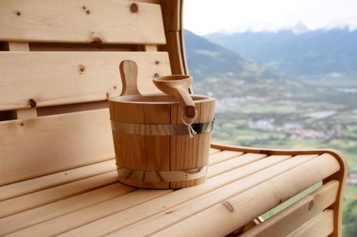 a wooden container with two wooden spoons sitting on a bench at Ansitz Röfen in Burgusio